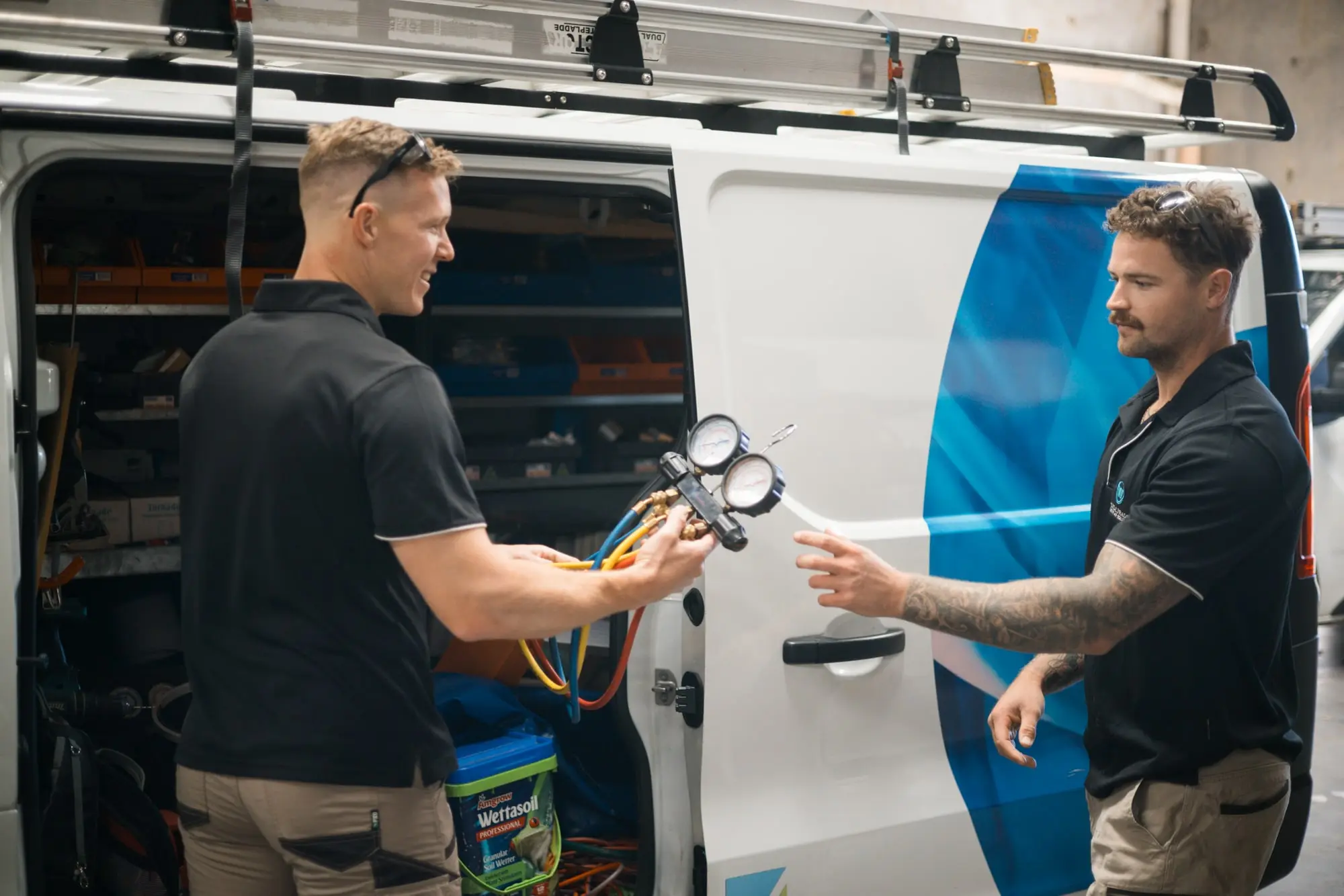 WestOz air conditioning technicians preparing diagnostic tools from a service vehicle before a job