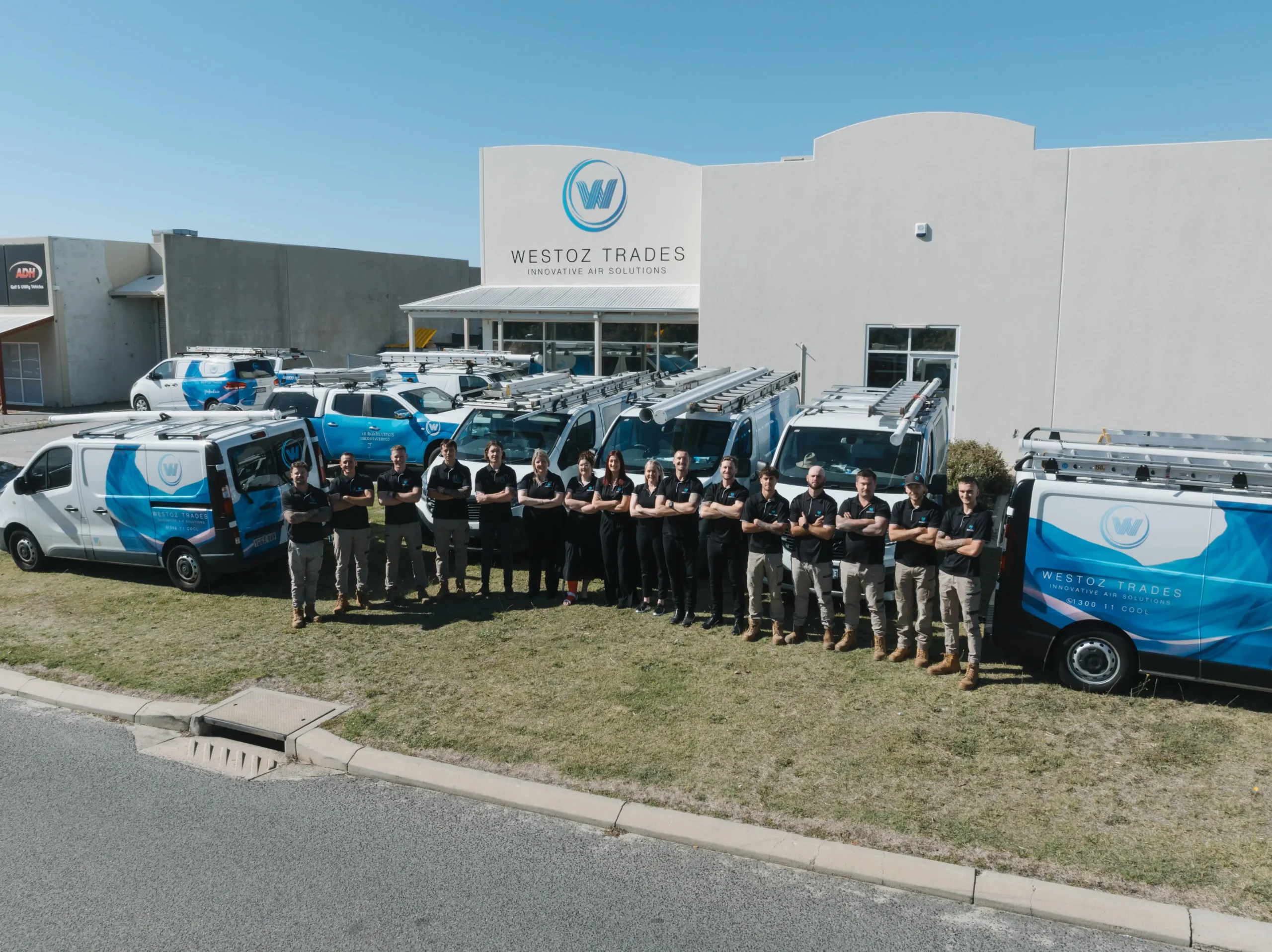 The WestOz Trades team standing outside their Wangara office with service vehicles, ready to support residential and commercial air conditioning clients.